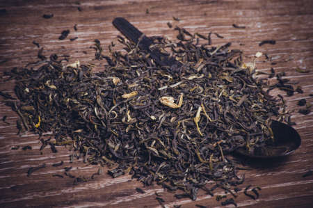 dried green tea leafs  on spoon on wooden backgroundの写真素材