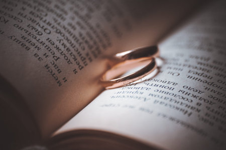 two wedding  rings laying on open bookの写真素材