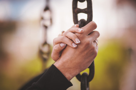 couple holding hand together on metal chainの写真素材