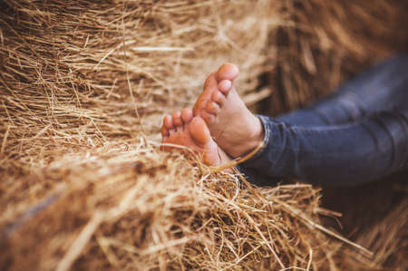 barefoot girl legs on haystack no faceの写真素材