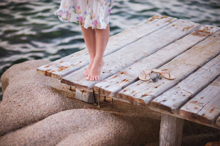 barefoot girl on wooden bridge above water no faceの写真素材
