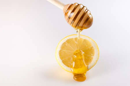 honey dripping on slice of lemon isolated  on whiteの写真素材