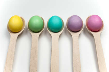colourfull easter eggs in wooden spoons isolated on white backgroundの写真素材