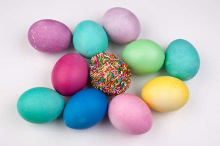 colored easter eggs and one covered with sprinkles isolated on whiteの写真素材