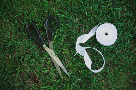 Satin white ribbon and scissors on the grass