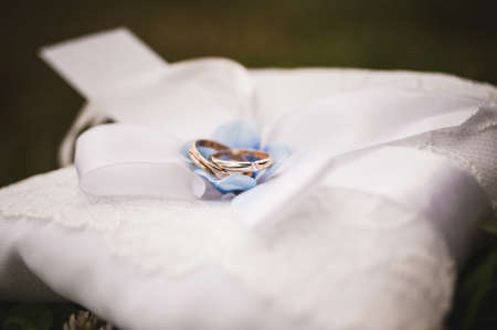 two gold wedding rings on a pillowの写真素材