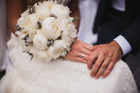 hands with rings bride and groom with wedding bouquet.