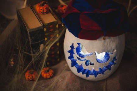 White halloween pumpkin head in clown hat with burning candles . Halloween holidays art design, celebration.の写真素材