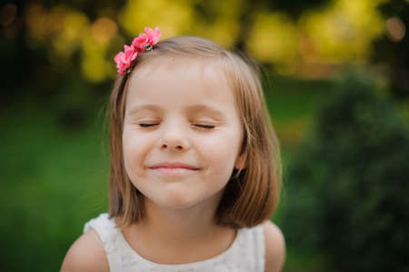Outdoor close up portrait of a cute young girl smiling in parkの写真素材