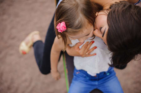 Loving mother kissing her daughter in parkの写真素材