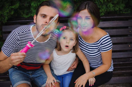 Family with daughter Playing With Bubbles In Gardenの写真素材