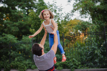 father having fun and throwing up his daughter in the parkの写真素材