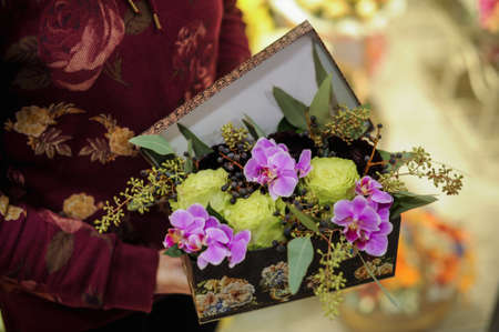 Close up carnation rose orchid flower bouquet in box in handsの写真素材