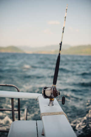 reel on fishing rod in chrome holder on a boatの写真素材