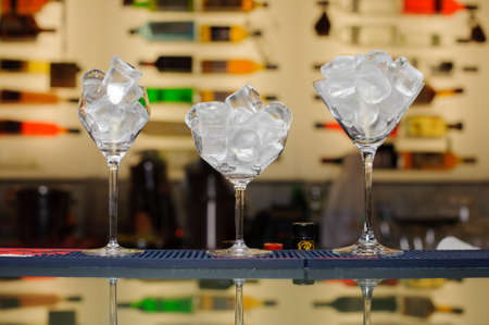 three glasses with ice on the bar bottles on backgroundの写真素材