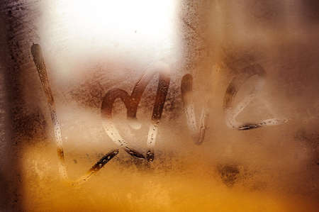 Love written sign on foggy window with heart instead of o letter . backgroundの写真素材