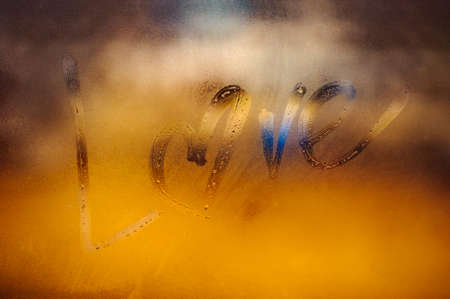 Love written sign on foggy window with heart instead of o letter . backgroundの写真素材