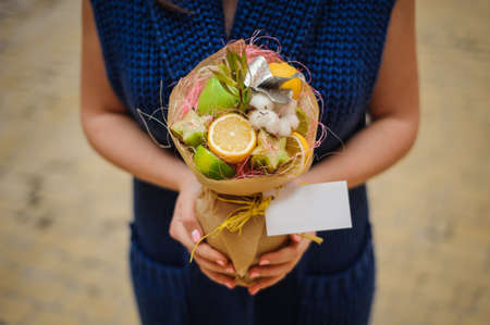 The original unusual edible bouquet of vegetables and fruits  in woman hands  with cardの写真素材