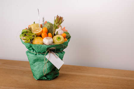 The original unusual edible bouquet of vegetables and fruits on  wood with cardの写真素材