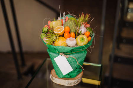 The original unusual edible bouquet of vegetables and fruits on  wood with cardの写真素材