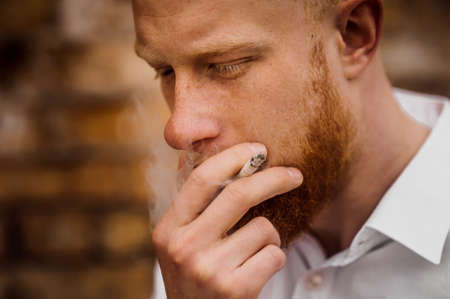 portrait of smoking young red hair man with beard  horizontalの写真素材
