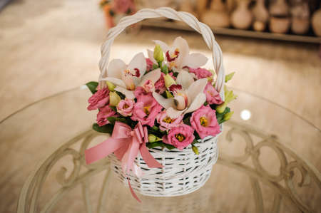 beautiful pink bouquet of mixed flowers in basket on glass tableの写真素材