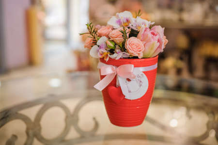 beautiful pink bouquet of mixed flowers in basket on glass tableの写真素材