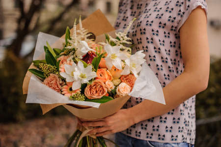 Bouquet of the different mixed  orange flowers in woman handsの写真素材