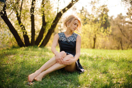 Pretty blond girl sitting on the grass in parkの写真素材