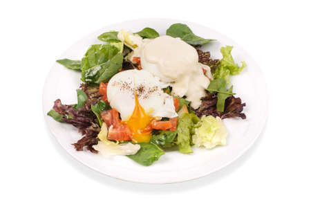 Eggs Benedict- toasted English muffins, salmon, poached eggs, and delicious buttery hollandaise sauce on salad isollatedの写真素材