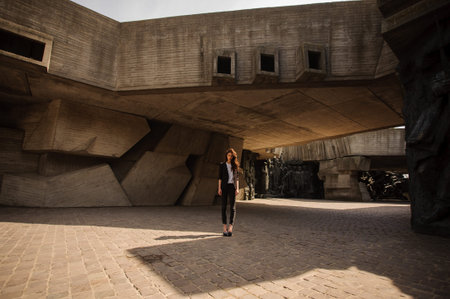 Young brunet woman standing outside in black jacket, jeans wearing hills  looking in camera . horizontalの写真素材