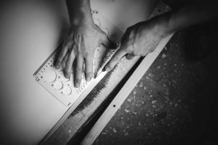 close up of  hands cutting paper with knife and ruler black and whiteの写真素材