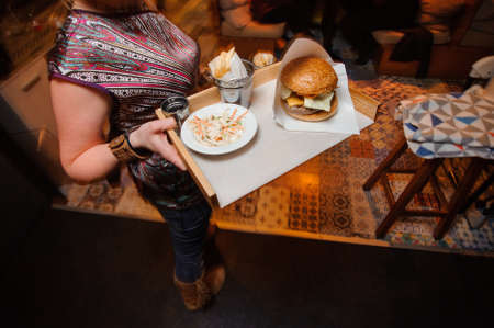 Waiter woman with hamburger and sides on plateの写真素材