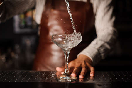 Barman pouring , splashing cocktail into a champagne glass and making a splash. no faceの写真素材