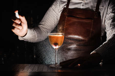Expert barman is spraying on cocktail at night clubの写真素材