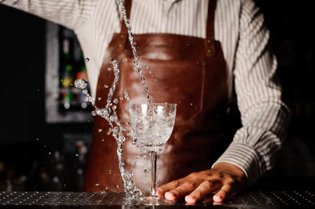 Water splashes out of the glass infront of barmanの写真素材