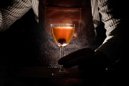 Expert barman is spraying on cocktail at night club close upの写真素材