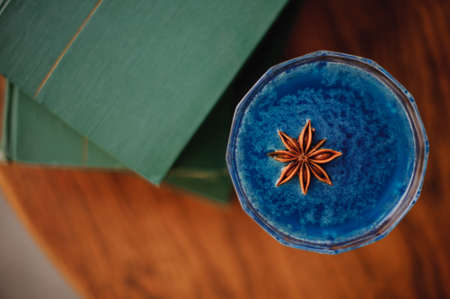 Blue cocktail with Star Anise on bar next to books top viewの写真素材
