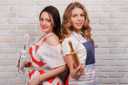 Two happy women housewife in apron at kitchen.の写真素材