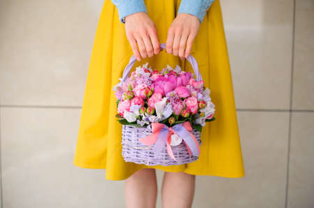 girl holding beautiful pink bouquet of mixed flowers in basket no faceの写真素材