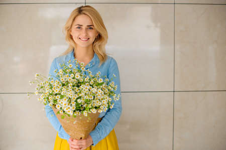 girl holding bouquet of camomiles in paperの写真素材