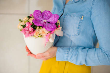 girl holding beautiful pink bouquet of mixed flowers in white vaseの写真素材