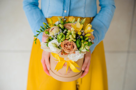 girl holding beautiful mix flower bouquet in a round box with lid