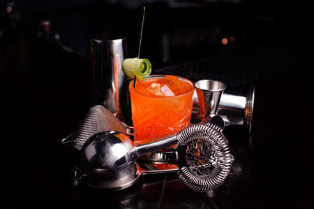 Red cocktail drink with ice. stainless steel cocktail bar tools and shaker.の写真素材