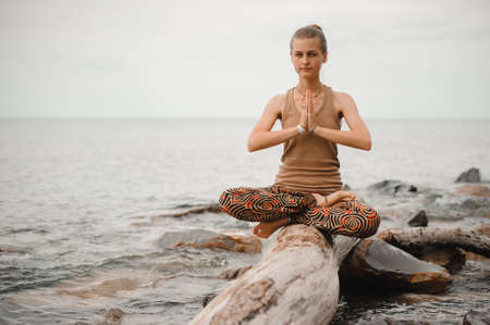 Woman meditating at the beach . yoga retreat. namaste in a lotus poseの写真素材