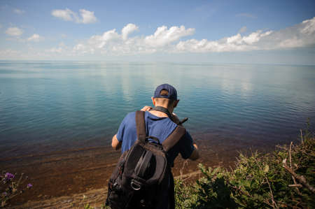 photographer man from behind taking photo, photographing lakeの写真素材