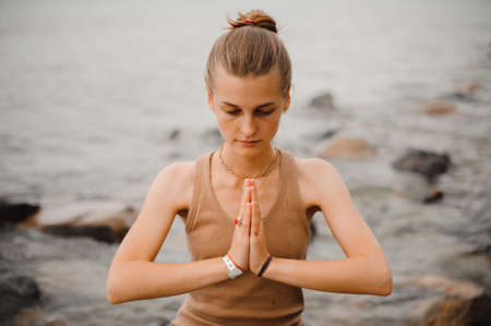 beautiful woman performing namaste with closed eyes gesture on beachの写真素材
