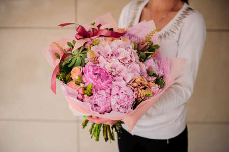 Beautiful bouquet of pink flowers in handsの写真素材