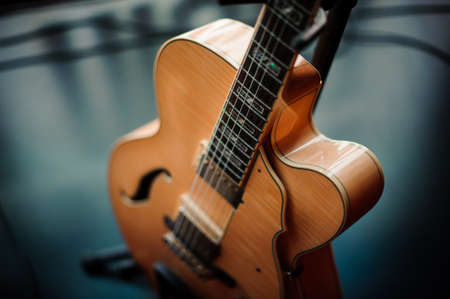 six-string acoustic guitar on a stand on stageの写真素材