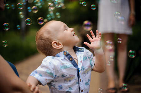 happy Boy playing catch soap bubbles outdoorsの写真素材